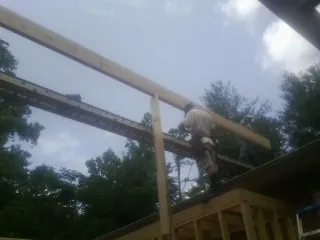 Carpenter setting a ridge beam over a new addition frame — Ice Dam Removal by Roofing Brothers in Auburn Hills