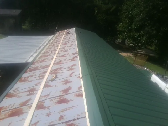 Old rusted panels beside newly installed green metal roofing — Wind Damage Roof Repair by Roofing Brothers in Auburn Hills