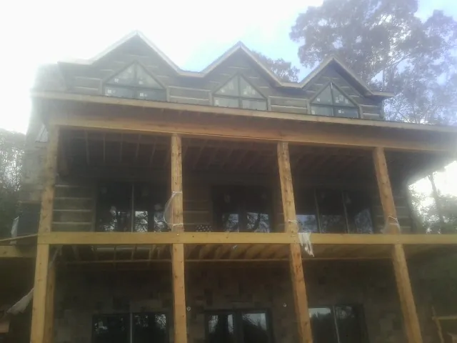 Dormers and porch framing on a large log home under construction — Roof Coating work by our crew in Auburn Hills