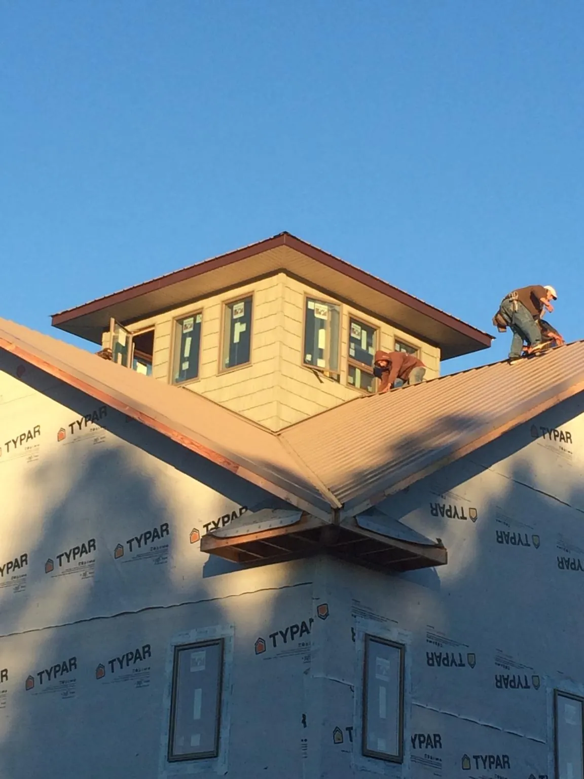 Roofers working around a rooftop cupola on a new metal roof at sunset — Roof Waterproofing in Auburn Hills by Roofing Brothers